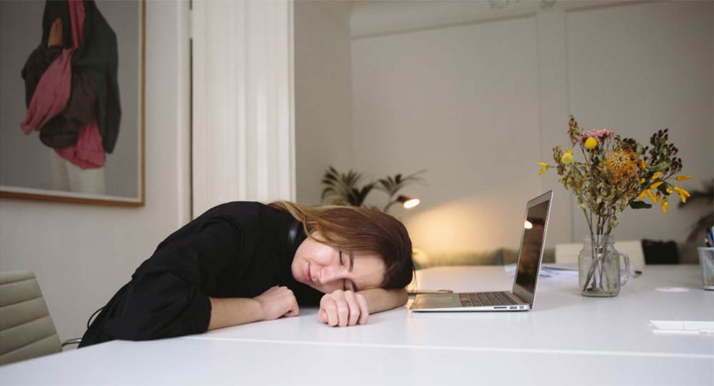 A young woman who has fallen asleep at the dining room table